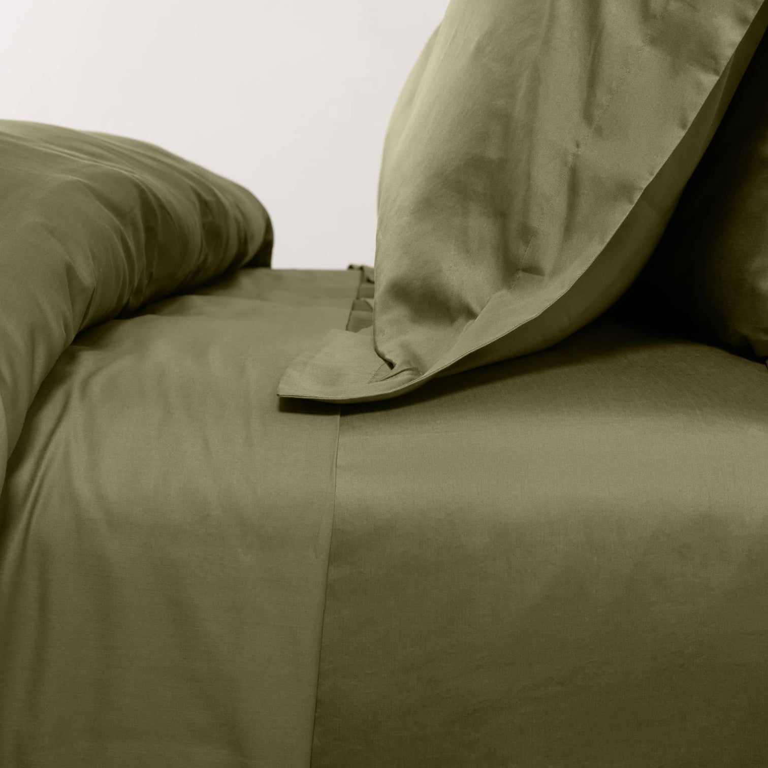 Olive green bed with neatly arranged pillows and duvet.
